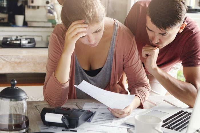 young couple calculating their domestic budget together kitchen trying save money buying new car having stressed frustrated looks unhappy woman showing unpaid bill her husband
